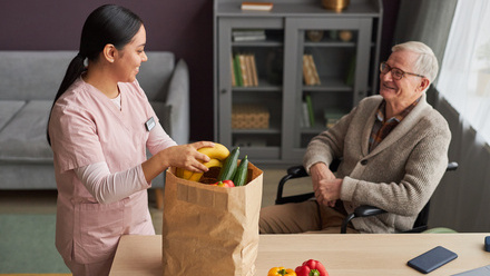 Care worker unpacking groceries for man in wheelchair.jpg